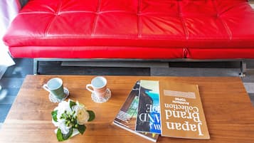 A red leather sofa, a wooden coffee table with a book and two cups.