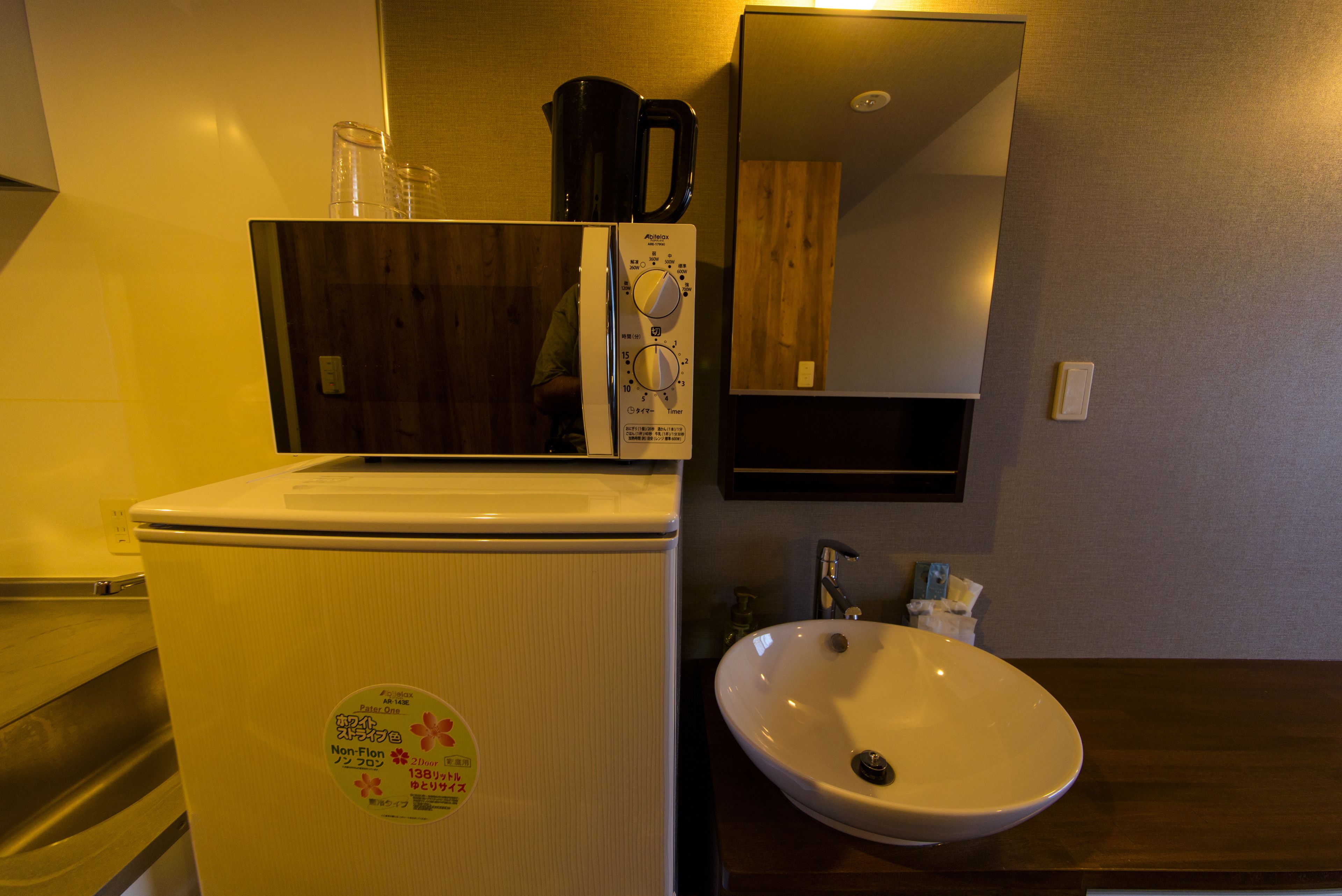 Une petite salle de bain avec un lavabo blanc, un miroir et un réfrigérateur.