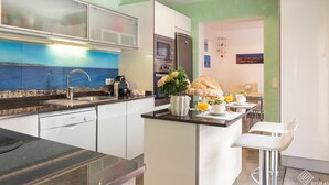 A modern kitchen with a view of the sea, a dining area with a table set for two, and a refrigerator. - Fonoll Mari - Beautiful house two minutes from the beach in S'Illot, Manacor (Manacor)