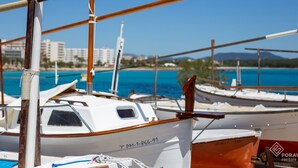 A marina with several boats docked, a clear blue sky, and a distant view of buildings and hills. - Fonoll Mari - Beautiful house two minutes from the beach in S'Illot, Manacor (Manacor)