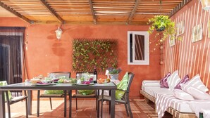 A covered patio with a table set for dining, a sofa, and a wall-mounted plant. - Fonoll Mari - Beautiful house two minutes from the beach in S'Illot, Manacor (Manacor)