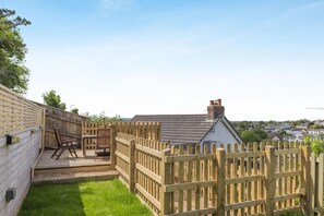 Un jardin avec une terrasse en bois, une table et deux chaises.