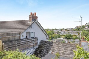 A residential building with a sloped roof, a chimney, and a small porch with steps leading up to a door.