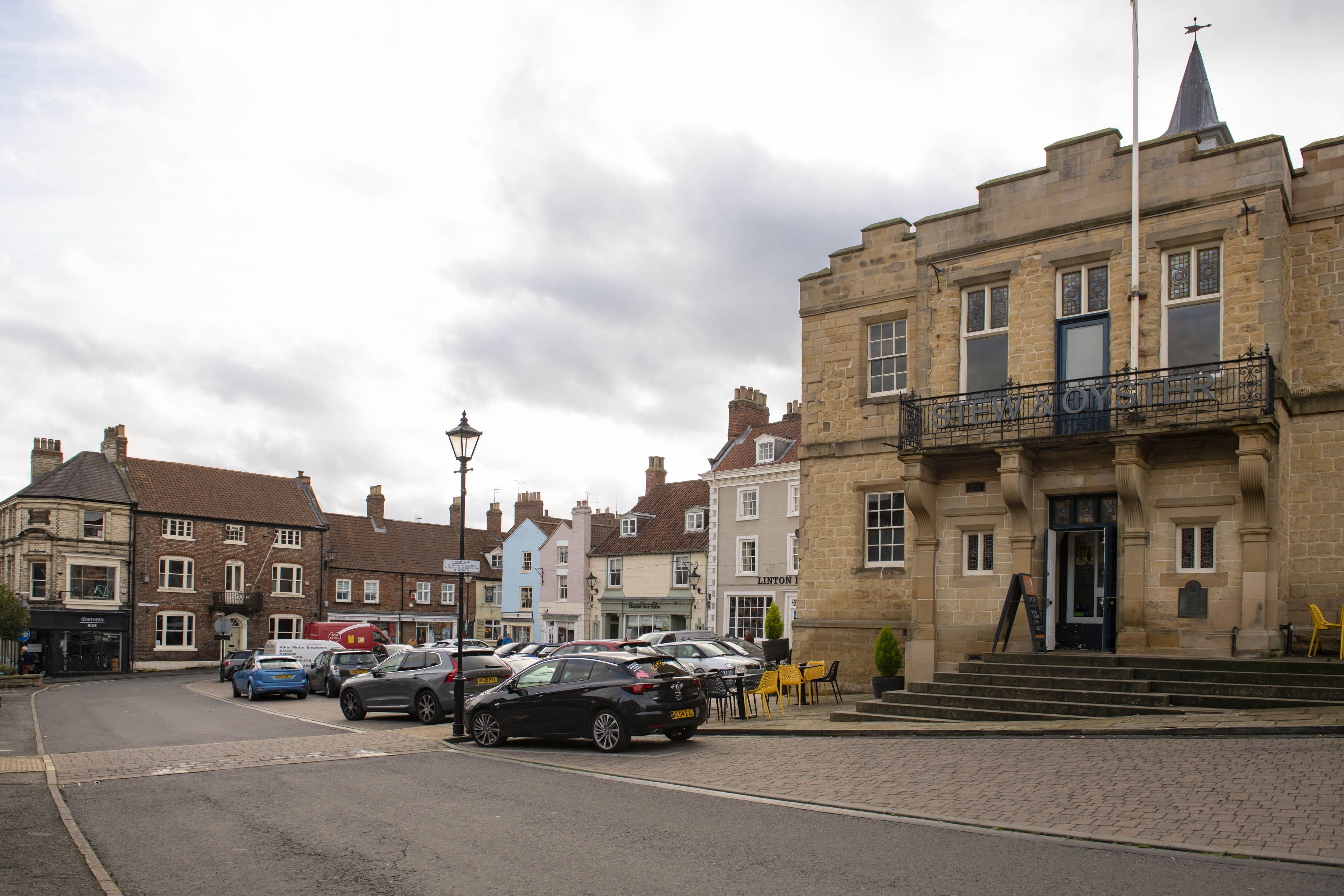 A street with parked cars and a building with a sign that reads 'STEW & OYSTER'.