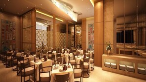 A spacious restaurant with multiple tables and chairs, a decorative ceiling, and a large wall with framed pictures. - Nataraj Sarovar Portico Jhansi (Jhansi)