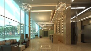A spacious lobby with a modern design, featuring a seating area with sofas and a large window offering a view of the city. - Nataraj Sarovar Portico Jhansi (Jhansi)