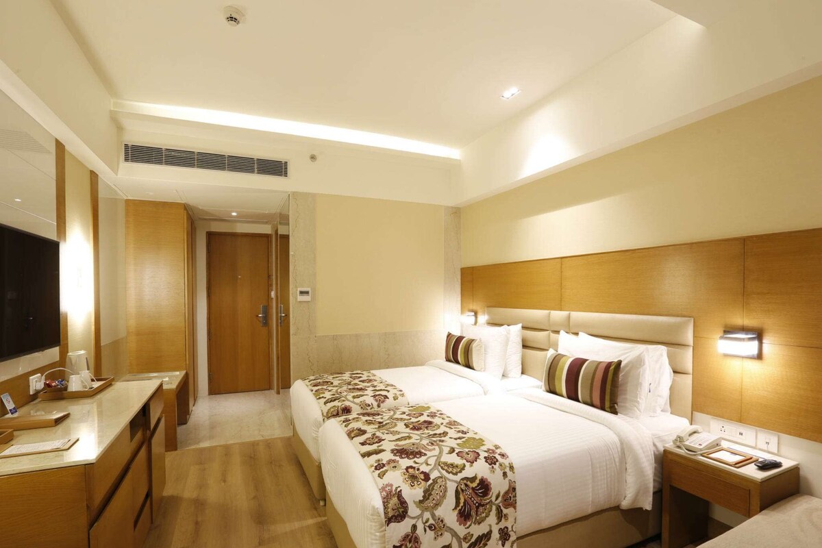 A hotel room with a large bed, bedside tables, a desk, and a TV.