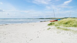 A sandy beach with a boat and windsurfers. - 3 bedroom awesome home in Højby (Højby)