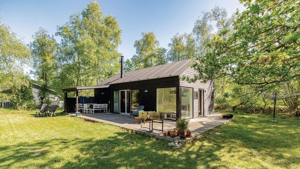 A modern house with a deck, large windows, and a chimney. - 3 bedroom awesome home in Højby (Højby)