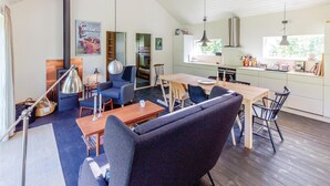 A modern kitchen with a dining area, featuring a large table, chairs, and a built-in oven. - 3 bedroom awesome home in Højby (Højby)