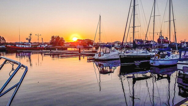 A marina with multiple boats docked at sunset.