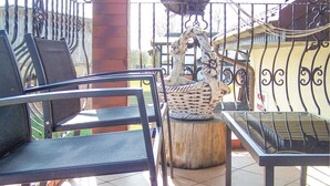 A patio area with a metal table and chairs, a wicker basket, and a decorative metal fence.