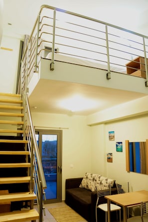 Un intérieur moderne avec un escalier, un canapé, une table et une porte donnant sur l’extérieur.
