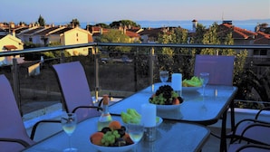 A dining table with a view of the city, set with fruits and wine glasses. - Alexanika Apartments (Sithonia)