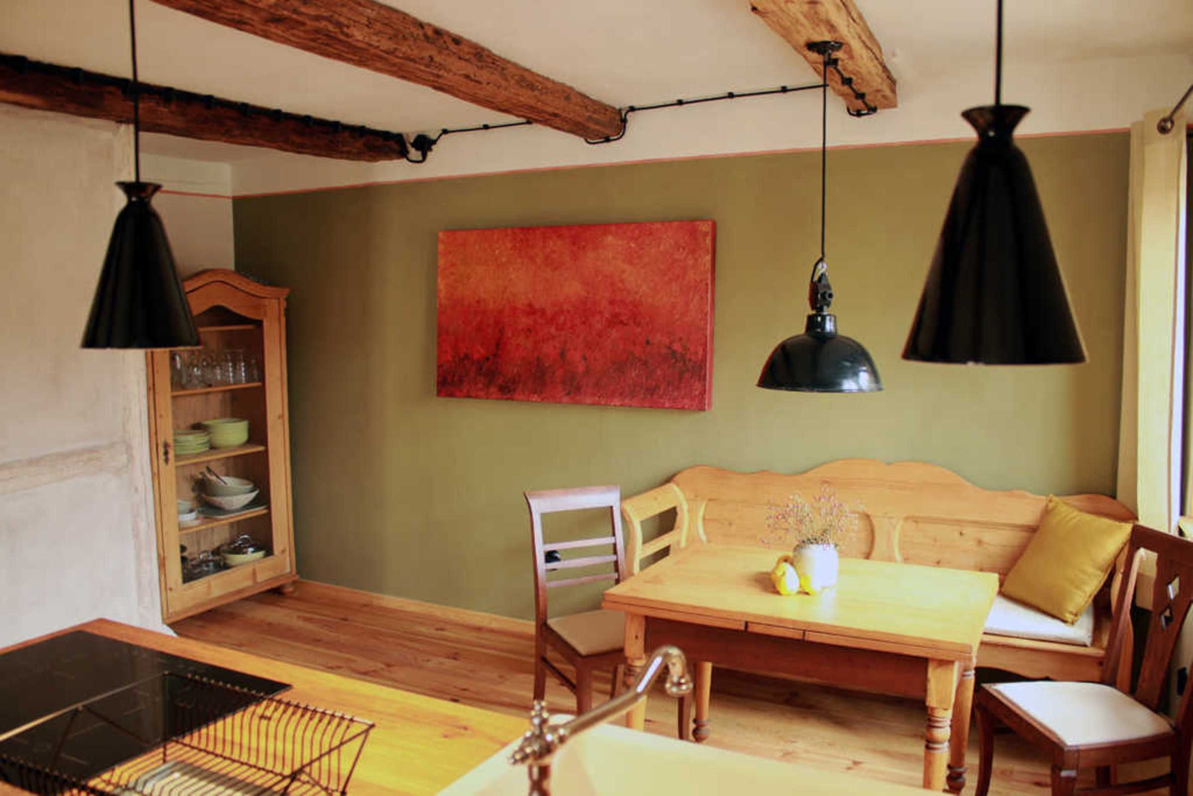 A dining area with a wooden table, chairs, a wooden cabinet, and pendant lights.