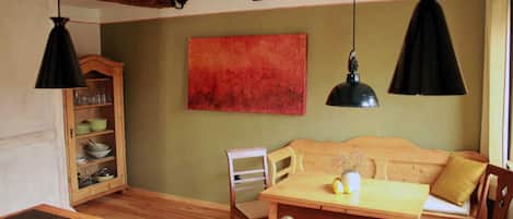 A dining area with a wooden table, chairs, a wooden cabinet, and pendant lights.