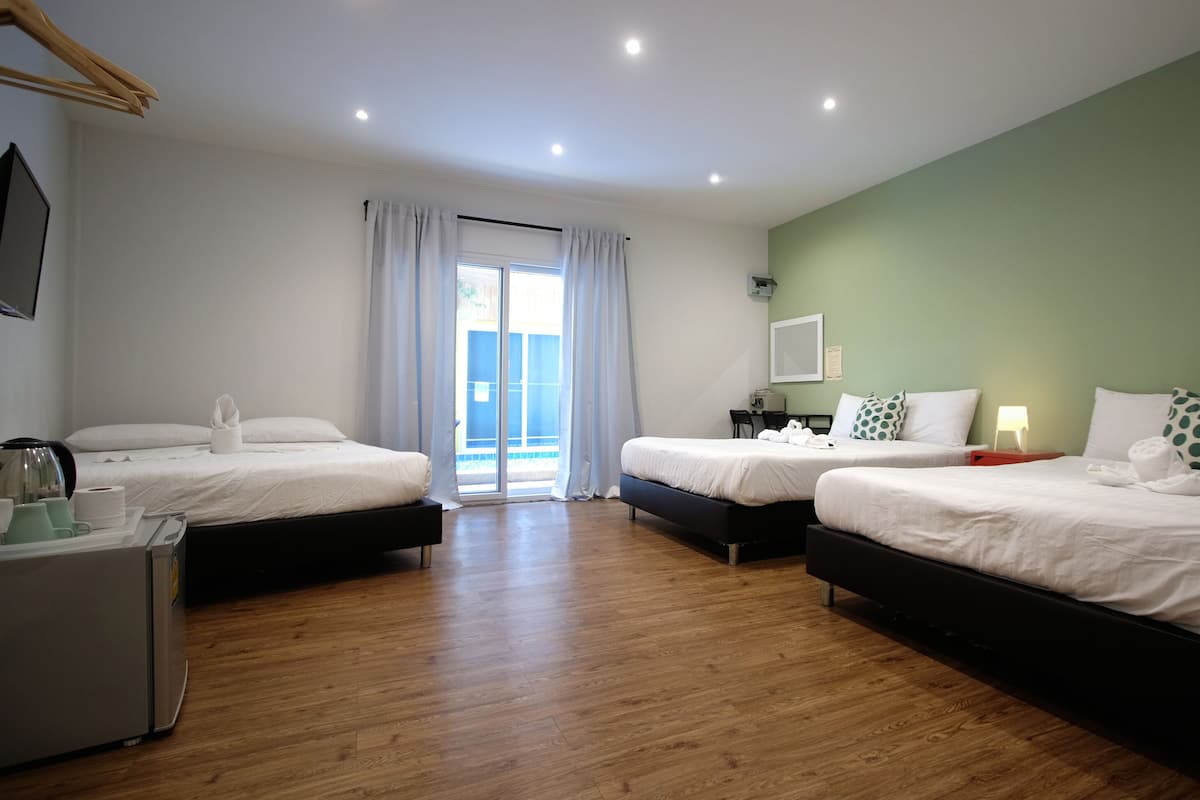 A hotel room with two beds, a desk, a chair, a small table, and a view of the outdoors.