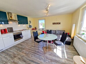 A modern kitchen with white cabinets, a dining table, and a sofa.
