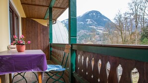 Ein Balkon mit Holzgeländer, einem Tisch mit violetter Tischdecke und einem Stuhl.