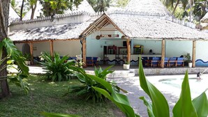 Un área de piscina con un bar llamado "POOL BAR" y varias zonas de estar con sillas.