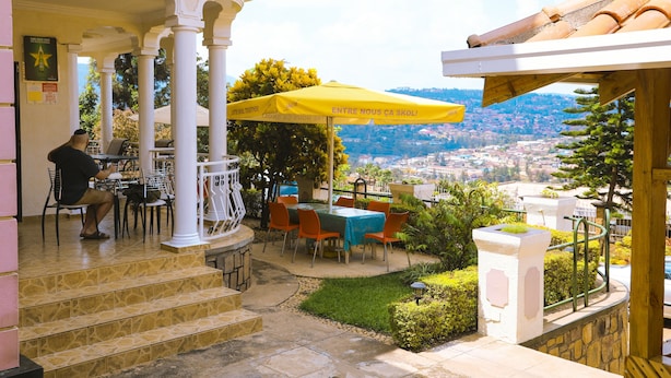 A terrace with outdoor seating, a yellow umbrella, and a view of a cityscape. - Step Town Hotel (Kigali)