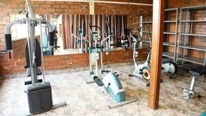 A gym with various exercise equipment, a brick wall, and a tiled floor. - Step Town Hotel (Kigali)