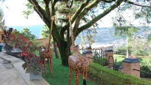 A garden with giraffe sculptures and a view of a town. - Step Town Hotel (Kigali)