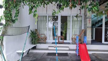 A covered outdoor area with a slide, a mop, and hanging plants.
