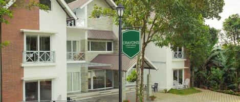 A guest house named Crayons with a brick facade, multiple balconies, and a paved courtyard with outdoor seating.