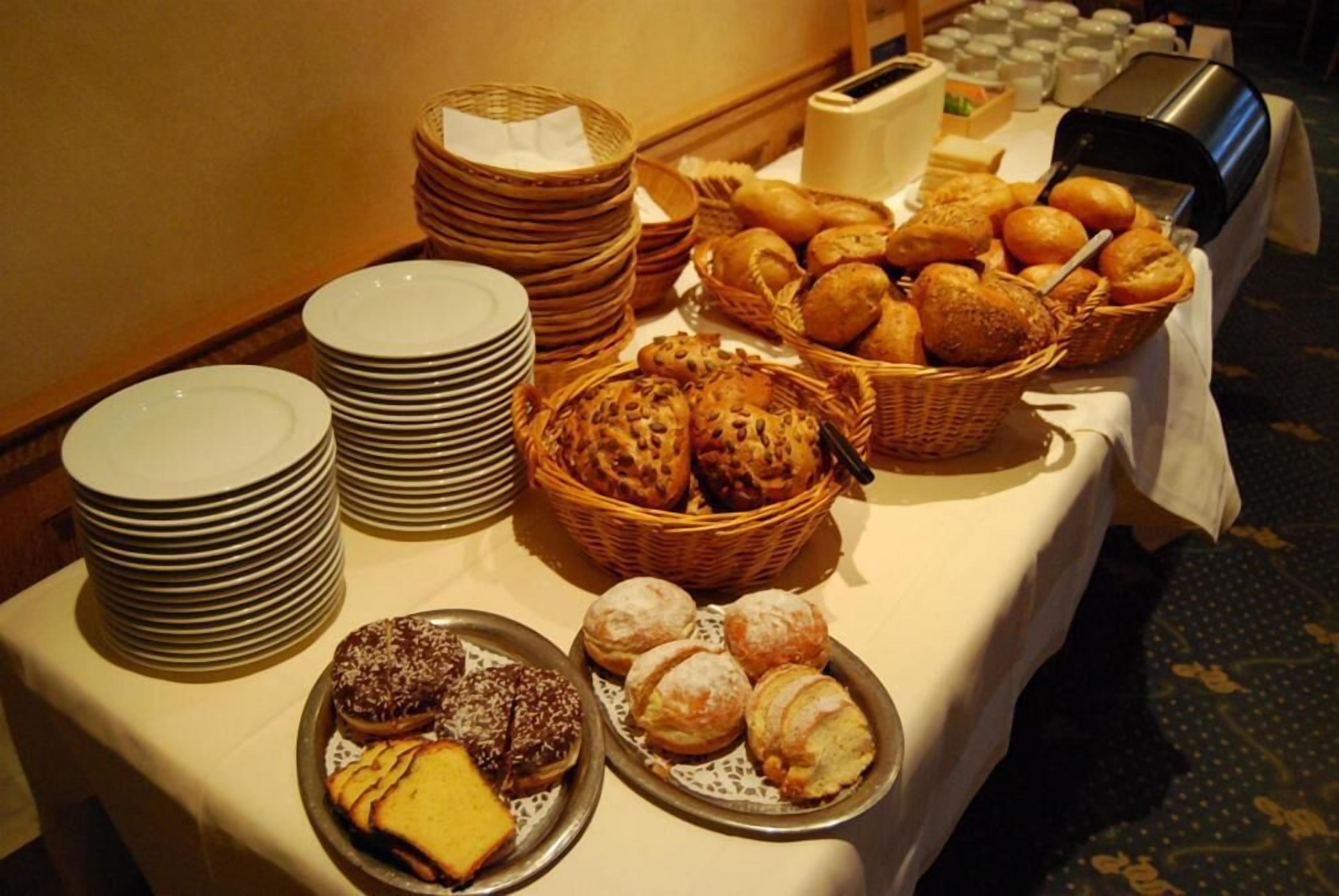Une table de buffet proposant divers types de pains, de viennoiseries et une machine à café.