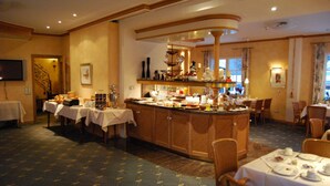 A hotel dining area with a central bar, multiple tables with white tablecloths, and chairs. - Landgasthof Schneider (Schmallenberg)