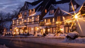 Ein traditionelles Gebäude im europäischen Stil mit vielen Fenstern und einem mit Schnee bedeckten Dach, vermutlich ein Hotel oder Gasthof.