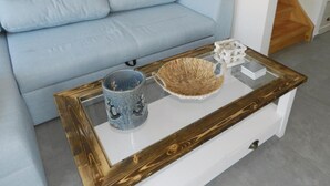 Ett vardagsrum med en ljusblå soffa, ett soffbord i glas med en träram, en keramisk mugg och en flätad korg.