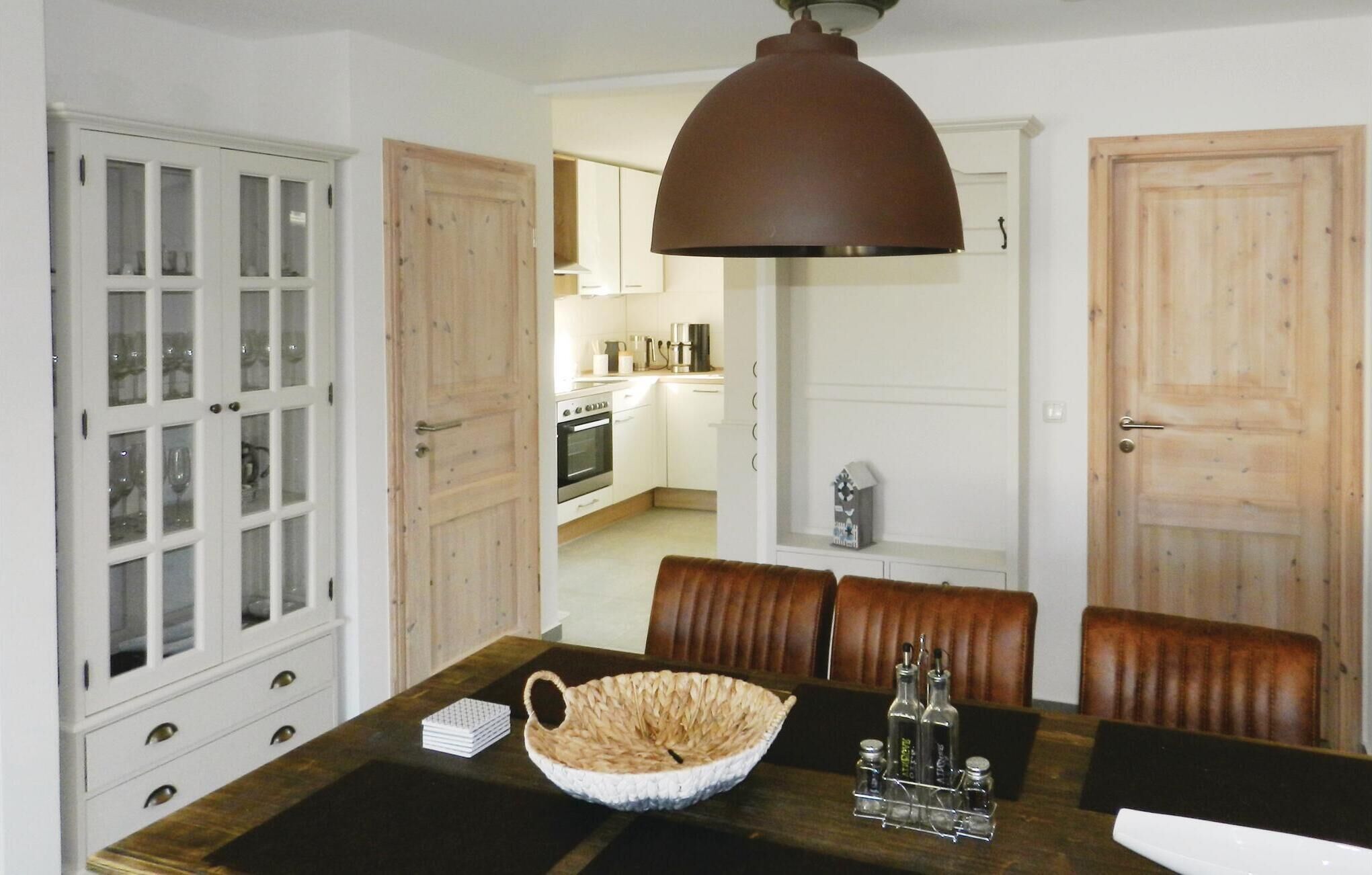 A dining area with a wooden table, chairs, a woven basket, and a hanging light fixture.