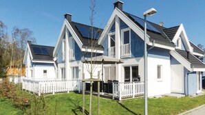 En rad moderna, tvåvåningshus med vita fasader och mörka tak, utrustade med balkonger och solpaneler.