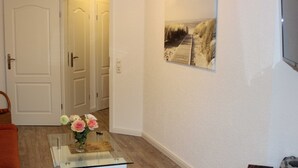 A room with a glass coffee table, a vase with flowers, a framed picture on the wall, and a door leading to another room. - Residenz Ostseestrand Nr. 11 - Residenz Ostseestrand Whg. 11with balcony (Scharbeutz)