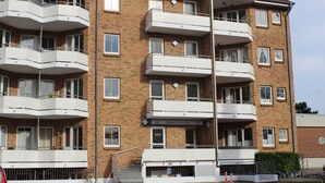 A multi-story residential building with balconies, a sign indicating 'Residences Osteestrand', and a parking area with cones. - Residenz Ostseestrand Nr. 11 - Residenz Ostseestrand Whg. 11with balcony (Scharbeutz)