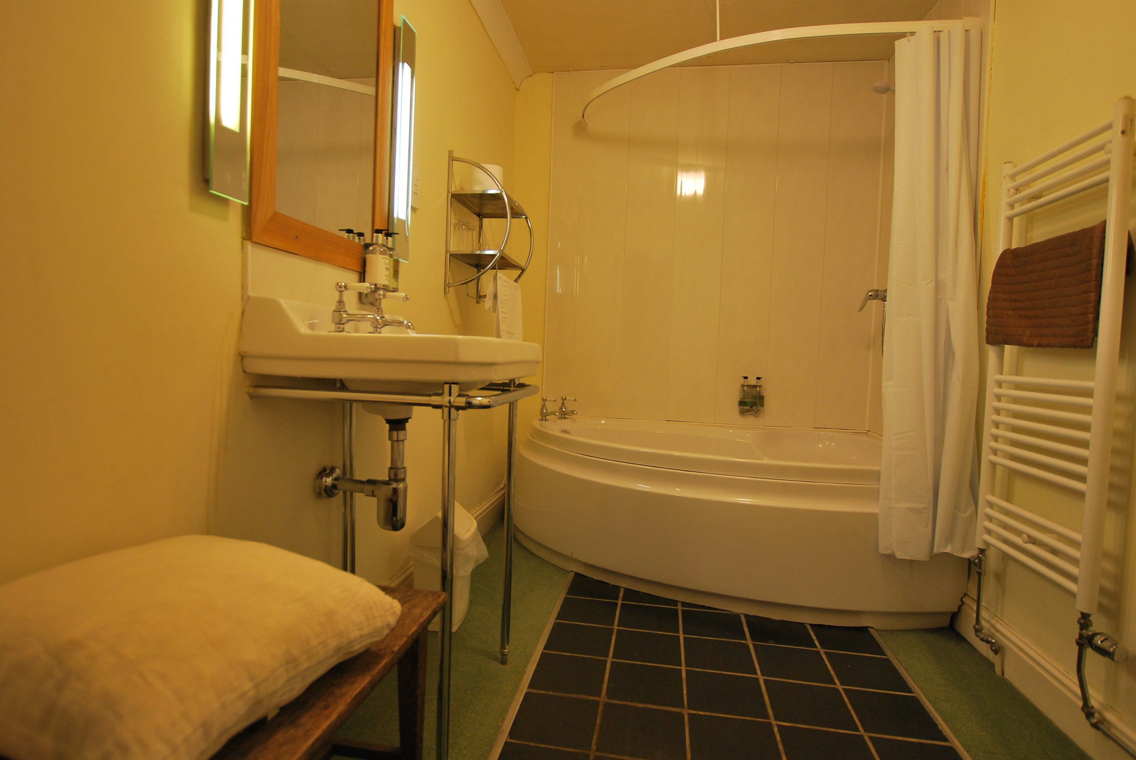A bathroom with a sink, mirror, and bathtub.