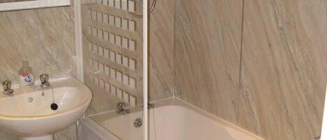 A bathroom with a white sink, a bathtub, and a shower enclosure.