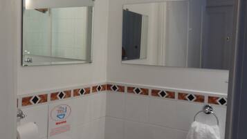 A bathroom with a toilet, a towel rack, and two mirrors.