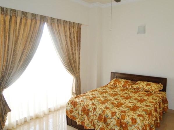 A bedroom with a bed, curtains, and a window.