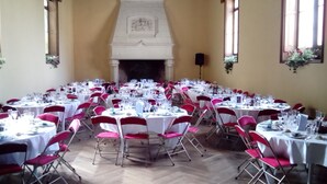 A banquet hall with multiple round tables, each set with white tablecloths and red chairs. - Château de la Court d'Aron (Saint-Cyr-en-Talmondais)