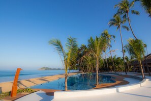 A pool area with a clear view of the ocean, surrounded by palm trees and a wooden deck. - Pristine Mermaid Resort (Ngapali)