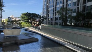 A modern urban setting with a water feature, seating area, and high-rise buildings in the background. - The Base Central Pattaya by Minsu (Pattaya)