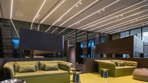 A modern lounge area with sofas and a yellow table, featuring a contemporary design with geometric patterns on the walls and ceiling. - The Base Central Pattaya by Minsu (Pattaya)