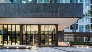 A modern building with large glass windows, a dark facade, and a well-lit entrance area with outdoor seating. - The Base Central Pattaya by Minsu (Pattaya)