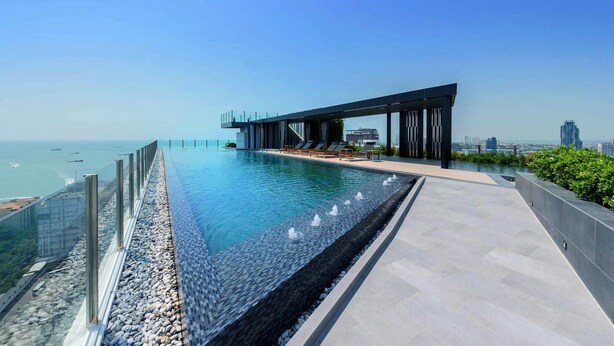 A rooftop infinity pool with a modern architectural design, overlooking a cityscape and the sea. - The Base Central Pattaya by Minsu (Pattaya)