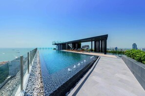 A rooftop infinity pool with a modern architectural design, overlooking a cityscape and the sea. - The Base Central Pattaya by Minsu (Pattaya)