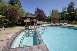 A swimming pool with a brick border, a lifeguard station, and lounge chairs.