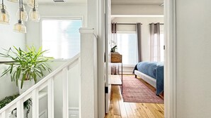 A hallway leading to a bedroom with a bed, a nightstand, and a potted plant. - Walnut Mews - Quiet Creekside townhome next to Pearl Street (Boulder)